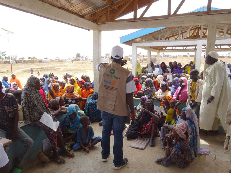 Families crowding around aid worker giving instructions