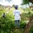 Person wearing IOM shirt stands in a field with people sitting around her socially distanced