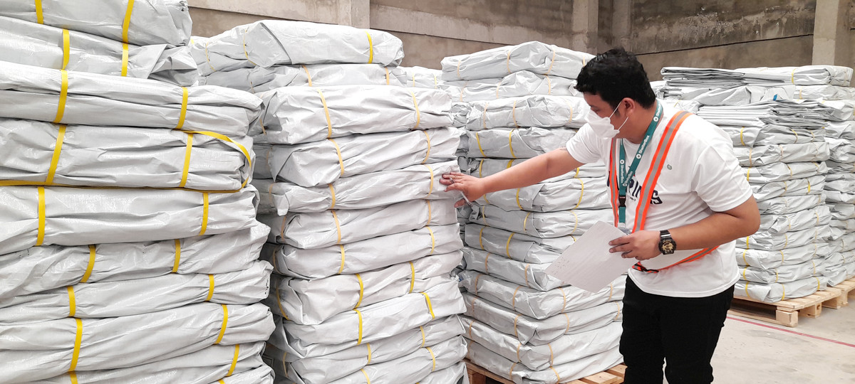 A man inspects ShelterBox aid items piled in a warehouse