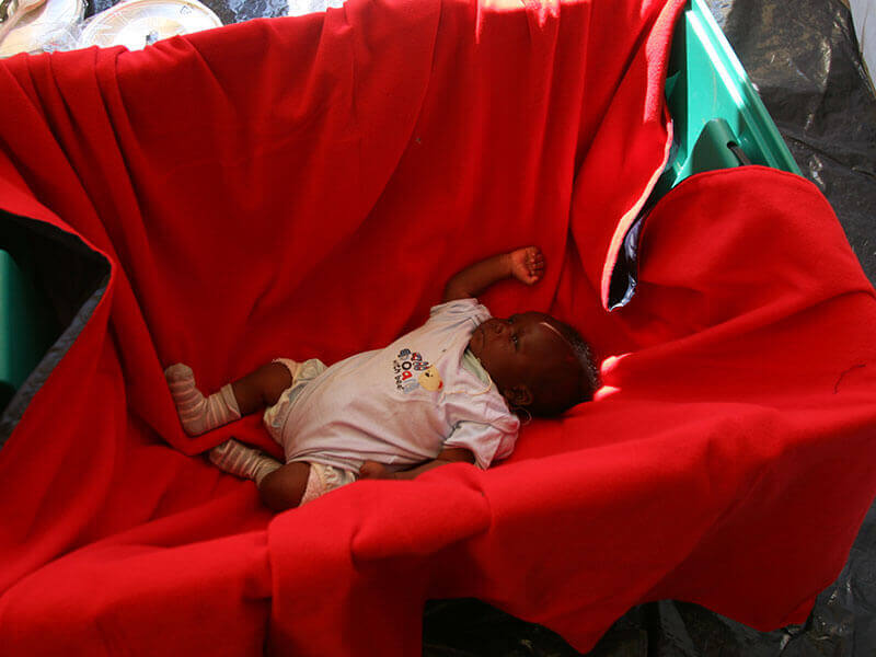 A new born baby sleeping on a blanket in a ShelterBox