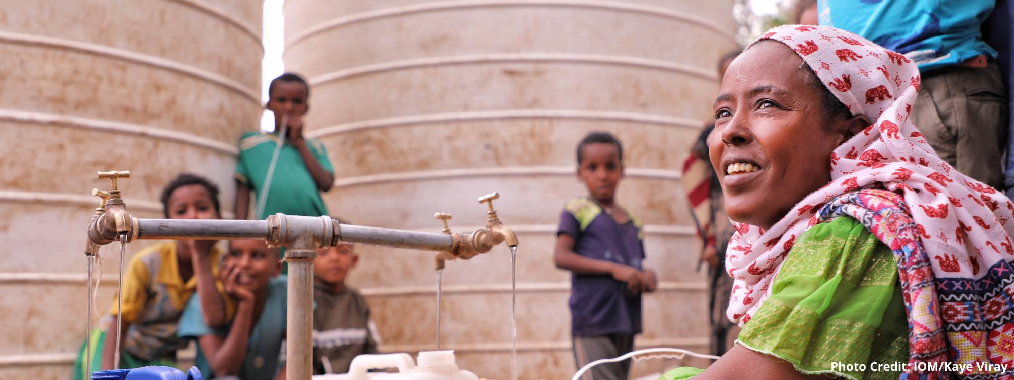 Woman crouching next to a water filling station