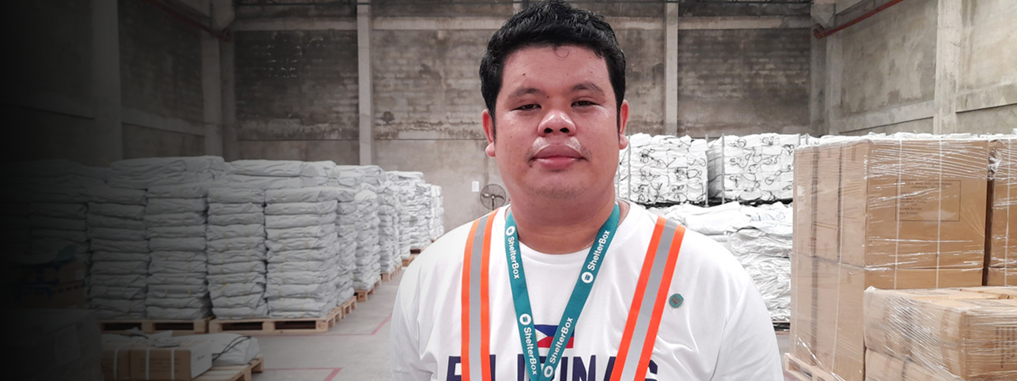 Domi looking at the camera, wearing his ShelterBox lanyard and a safety vest