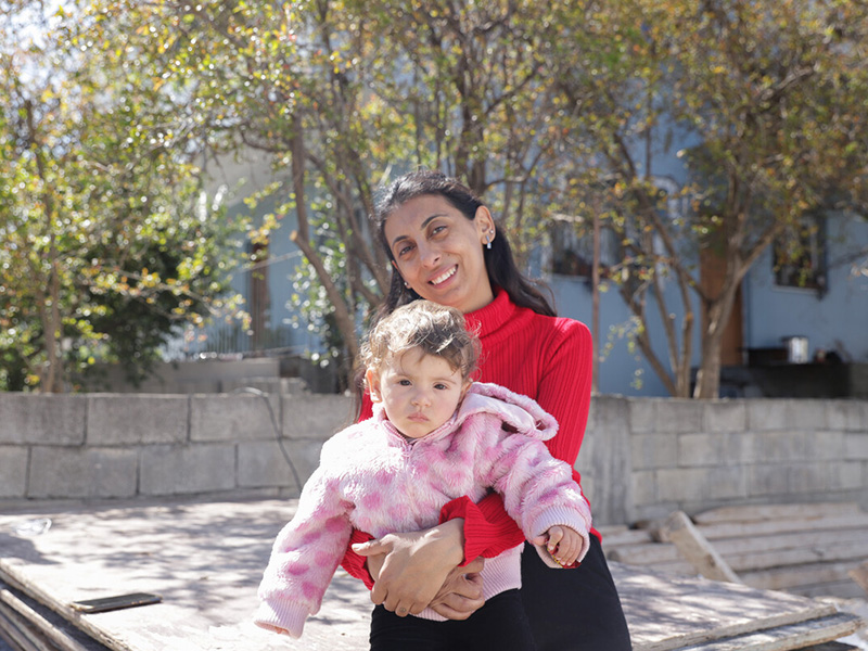 A woman stands holding a child