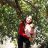 A woman stands under a tree holding her infant daughter